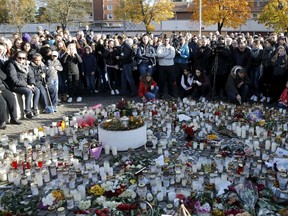 A moment of silence is observed by people at the memorial site outside Kronan school in Trollhattan, Sweden, October 25, 2015. A masked swordsman who killed a teaching assistant and a boy and wounded two others sought out his victims, all with immigrant backgrounds, by skin colour in an attack that has fuelled fears that a big refugee influx is polarizing Swedish public opinion. REUTERS/Adam Ihse/TT News Agency