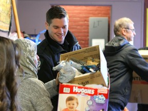 EPS Cst. Darren Taitinger joins an assembly line of volunteers unloading donations of clothing, toys and household items for Syrian refugees at the Edmonton Emergency Relief Services Society on Dec. 22, 2015. CLAIRE THEOBALD Edmonton Sun