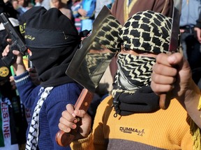 A masked Palestinian boy holds a chopper during a rally organized by Islamic Jihad in Rafah in the southern Gaza Strip December 18, 2015. REUTERS/Ibraheem Abu Mustafat