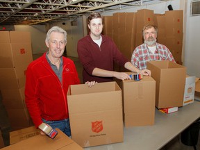 Volunteers Robert Szijgyarto, left, and Liam Rafferty help Neil Ainsworth, the logistics coordinator for the Salvation Army Christmas Hamper Fund, tape up the more than 3,000 boxes at Portsmouth Olympic Harbour in Kingston, Ont. on Friday December 18, 2015. Ainsworth wants to get  as many boxes ready before the flurry of activity that will take place on Monday when the trucks arrive and the packing begins. Julia McKay/The Kingston Whig-Standard/Postmedia Network