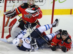 Calgary Flames Karri Ramo looks for the puck as TJ Brodie collides with Blake Wheeler of the Winnipeg Jets during NHL hockey in Calgary, Alta. on Tuesday December 22, 2015. Al Charest/Calgary Sun/Postmedia Network