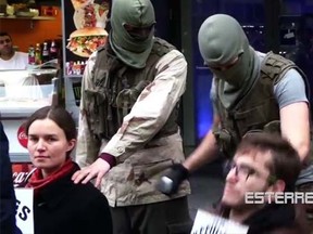 A video posted online this week, which said the display was by the anti-immigrant Identitaeren group, shows two masked men dressed in military fatigues pretending to behead a man and a woman holding signs that say, "refugees welcome."(Esterreicherr/YouTube screengrab)