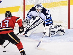 Calgary Flames left wing Johnny Gaudreau (13) moves in on Winnipeg Jets goalie Michael Hutchinson (34) during a game at Scotiabank Saddledome last season. The Flames won that game 4-1, and the Jets will go with Hutchinson Saturday when the teams meet. (Postmedia file photo)