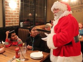 Dev and Riya Patel listen closely to Santa Claus. (Laura Broadley/Goderich Signal Star)