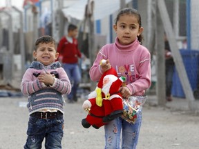 Displaced Christian children who fled Islamic State carry gifts given to them at Zayuna camp in Baghdad December 23, 2015. REUTERS/Khalid al Mousily