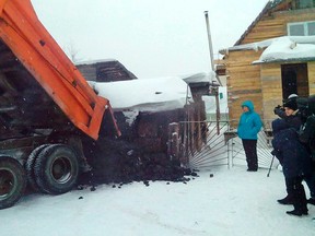 In this photo taken on  Wednesday, Dec. 23, 2015, Yelena Salnikova, in a blue jacket, a nurse from a small town of Berezovskiy, Russia, gets a truck full of coal from authorities in the Kemerovo coal-rich region for losing 30 kilos (66 pounds) in weight. Governor of Russia's Kemerovo region Aman Tuleyev promised earlier this year to reward locals with 1.5 metric tons of coal for every ten kilos lost, everyone thought it was a just joke. (Anton Gorelkin/ Kemerovo Regional Administration Press Service photo via AP)