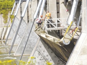 Workers take safety precautions on the Springbank Dam, while divers were in the water beneath it during testing in the summer. A group of Londoners pushing to have the dam fixed is calling for public support. (MIKE HENSEN, The London Free Press)