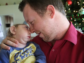 In this Tuesday, Dec. 22, 2015 photo, Brandon Buell holds his year-old son Jaxon, who was born with a rare condition that prevented much of his brain from forming and left half his skull flat, in Tavares, Fla. Brandon and his wife said presents have piled up for Jaxon, whose Christmas card with Santa became an Internet sensation. (Tom Benitez/Orlando Sentinel via AP)