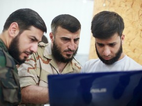 Zahran Alloush (C), commander of Jaysh al Islam, looks at a screen during a conference in the town of Douma, eastern Ghouta in Damascus, Syria August 27, 2014. The head of the most powerful Syrian insurgent group in the rebel-held suburbs of Damascus was killed on Friday in a Russian air strike on the secret headquarters of his group, rebel sources said. The Syrian army confirmed the death of Alloush, whose Jaysh al Islam grouping has thousands of fighters and is the biggest rebel faction in the area. Picture taken August 27, 2014. REUTERS/Bassam Khabieh