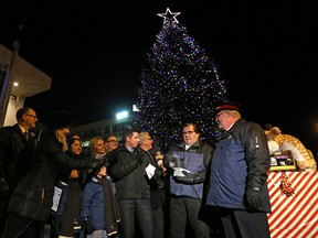 Homeowner Ron Gerth (second right) lights the Christmas tree he donated outside city hall along with Mayor Brian Bowman and his family and assorted city staff on Thu., Nov. 26, 2015. The city is now collecting real Christmas trees to recycle. (Kevin King/Winnipeg Sun/Postmedia Network)