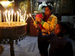 A visitor lights candles in the Church of the Nativity, the site revered by Christians as Jesus' birthplace, ahead of Christmas in the West Bank town of Bethlehem, December 23, 2015. REUTERS/Ammar Awad