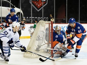 With a car and a dark background behind him, Maple Leafs center Shawn Matthias tries to score against Islanders goalie Thomas Greiss on Sunday night at the Barclays Center. (AP/PHOTO)