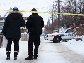 A police officer speaks to an area resident as police continue to investigate at the scene of an incident near 79 Street and Whyte Avenue, in Edmonton Alta. on Monday Dec. 28, 2015. David Bloom/Edmonton Sun