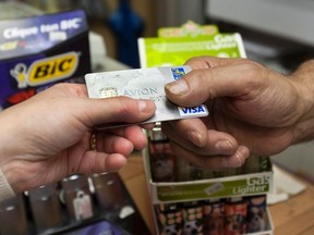 A consumer pays with a credit card at a store Tuesday, July 6, 2010 in Montreal. Canadian household debt has climbed to record-high levels. With interest rates at historic lows, fretful economists and other experts are wondering how the overspending train can be stopped in 2016, and what will happen should rates start to climb as they are in the United States. (THE CANADIAN PRESS/Ryan Remiorz)