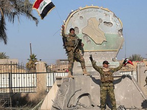 A member of the Iraqi security forces holds an Iraqi flag at a government complex in the city of Ramadi, Dec. 28, 2015. REUTERS/Stringer