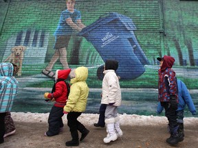 Grade 1 students from William Whyte Community School walk past the Simply Recycle mural on the side of Avenue Meats at the corner of Selkirk Avenue and McGregor Avenue.