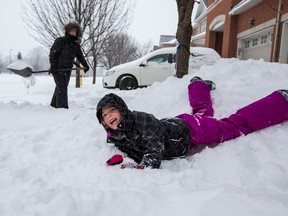 Five-year-old Tessa Snow plays while her mom Heidi Snow shovels during the first major snow fall of the season in Ottawa on Tuesday December 29, 2015. Errol McGihon/Ottawa Sun/Postmedia Network