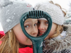 Stepsisters Emma Hitchen and Chloe Burns, both 8, look through the handle of a snow shovel while playing in the snow on Tuesday in Kingston. (Julia McKay/The Whig-Standard)