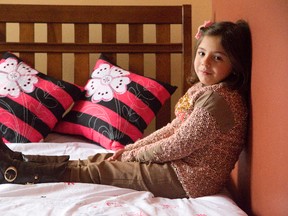 Six-year-old Syrian refugee Amina Chablot rests on a bed at the Cross Cultural Learner Centre Tuesday where she and her family have begun a new chapter of their lives. (DEREK RUTTAN, The London Free Press)