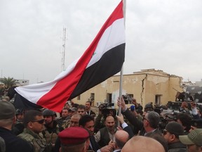 Iraqi Prime Minister Haider al-Abadi (centre, back to camera) holds an Iraqi flag in the city of Ramadi, December 29, 2015. Abadi on Tuesday visited Ramadi a day after the army retook the city centre from Islamic State, a victory that could help vindicate his strategy for rebuilding the military after stunning defeats in the past 18 months. (REUTERS/Stringer)
