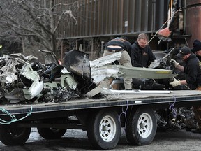Workers load the remains of a small plane that crashed into two office building in downtown Anchorage, Alaska, Tuesday, Dec. 29, 2015. The pilot was not authorized to fly the aircraft used in volunteer search-and-rescue missions, authorities said. (Bob Hallinen/Alaska Dispatch News via AP)