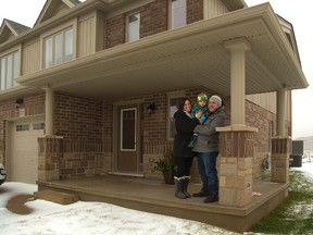 Dallas Hill, 2 is sandwiched between Nikki Tait-Hill and Braden Hill under their brand new porch adorning their in their newly moved in townhouse in London, Ont. on Tuesday December 29, 2015. (MIKE HENSEN, The London Free Press)