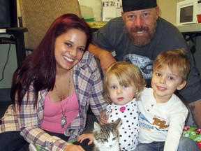 In this photo provided by the Riverside County Department of Animal Services, Scarlette Tipton, center, a 2-year-old cancer survivor with an amputated arm, her brother Cayden, 3, and parents Simone and Matt Tipton pose with a kitten who also suffered an amputation, at the agency's shelter in San Jacinto, Calif., Wednesday, Dec. 30, 2015. The Orange County family had been searching for a kitten to help their daughter, who was born with a rare form of cancer that led to having her left arm amputated when she was 10 months old. Doctors say Scarlette is now cancer free. The kitten, named Holly, suffered a severe injury and had her left foreleg amputated in December. (John Welsh/Riverside County Department of Animal Services via AP)
