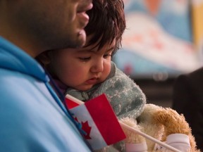 A young Syrian refugee is held by her father as they arrive at the Welcome Centre at Toronto's Pearson Airport on Dec. 18, 2015. (THE CANADIAN PRESS/Chris Young)