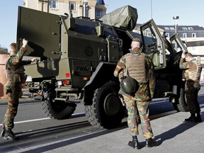 Belgian soldiers stand next to a military armoured vehicle as they patrol in central Brussels, December 31, 2015. Belgian police have held three more people after previously detaining six during house searches in Brussels in an investigation into a plot to carry out an attack in the city on New Year's Eve, prosecutors said on Thursday.    REUTERS/Francois Lenoir