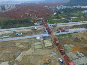 An aerial view shows trucks filled with mud leaving the site of a landslide which hit an industrial park on Sunday in Shenzhen, Guangdong province, China, December 22, 2015. REUTERS/Stringer