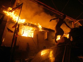 A resident jumps as fire engulfs houses in a poor neighbourhood of Tondo in Manila, Philippines, at the height of New Year celebrations on Jan. 1, 2016. The cause of the fire is still under investigation but a number of fires that occurred in the raucous New Year celebrations in the country are attributed to firecracker explosions. (AP Photo/Linus Escandor II)
