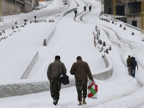 Lebanese soldiers and citizens walk on the snow as they carry their belonging in Behamdoun, Lebanon, January 1, 2016. REUTERS/ Jamal Saidi