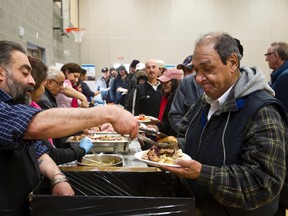 Roger Sarna (left), with Palace Banquets, serves dinner during the Bissell Centre's New Year's Day dinner held at the Boyle Street Plaza in Edmonton, Alta. on Tuesday, Jan. 1, 2013. The dinner, which provided 1,200 meals made with 65 turkeys and 35 hams, was held for the inner city community. It was prepared by Palace Banquets, which have been involved for the last 16 years. Ian Kucerak/Edmonton Sun/QMI Agency