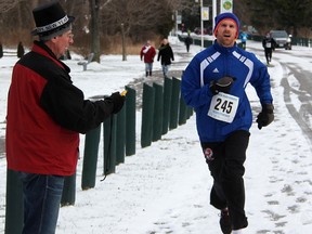 Wade Fleming races to the Canatara Park finish line in the annual Sarnia Roadrunners 7k Resolution Run Friday. About 50 people took part in this year's race, said club president Glen Crawford, pictured here timing Fleming's finish. Tyler Kula/Sarnia Observer/Postmedia Network