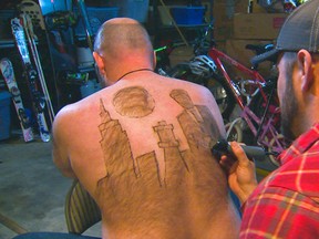 In this Dec. 30, 2015 photo provided by KTVB-TV, Tyler Harding, right, trims a design on Mike Wolfe out of his back hair in Nampa, Idaho. Wolfe and Harding meet up several times throughout the year to design a new creation on Wolfe’s back. The designs have since been compiled for a calendar. (Mike di Donato/KTVB via AP)