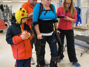 Wingham high school teacher Julie Sawchuk, who was struck by a car during the summer and suffered horrific injuries, walks in an exoskeleton with her son Oliver, 9, at Parkwood Hospital in London. Helping her is Barry Lynam, a physiotherapist assistant, and physiotherapist Kristin Wanless. (MIKE HENSEN, The London Free Press)