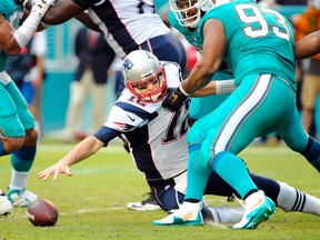 New England Patriots quarterback Tom Brady (12) reaches for a ball that he fumbled as Miami Dolphins defensive tackle Ndamukong Suh (93) holds his jersey Sunday at Sun Life Stadium. (Robert Duyos/USA TODAY Sports)