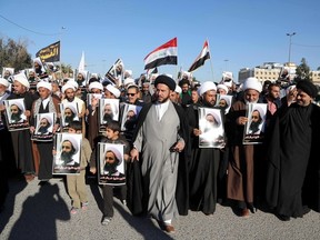 Iraqi Shiite protesters chant slogans against the Saudi government as they hold posters showing Sheikh Nimr al-Nimr, who was executed in Saudi Arabia last week, during a demonstration in Najaf, 100 miles (160 kilometers) south of Baghdad, Iraq, Monday, Jan. 4, 2016. (AP Photo/Karim Kadim)