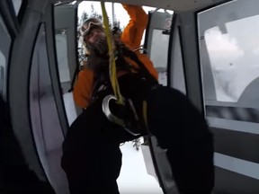 A screenshot captures the moment a rescuer swings into the Golden Eagle Express Gondola at Kicking Horse Mountain Resort on Sunday, Jan. 3, 2015. (YouTube)