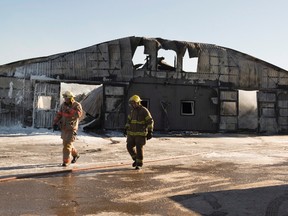 Firefighters walk past a barn that was destroyed by a fire at the Classy Lane Stables in Puslinch, Ont., on Tuesday, Jan. 5, 2016. More than 40 racehorses were killed when a fire tore through a barn the night before. THE CANADIAN PRESS/Hannah Yoon