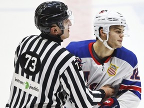 A referee holds back American forward Alex Debrincat after his game misconduct penalty during a world junior championship match against Canada in Helsinki on Dec. 26, 2015. (Roni Rekomaa/Lehtikuva via AP)