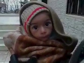A toddler is held up to the camera in this still image taken from video said to be shot in Madaya on January 5, 2016. Warnings of widespread starvation are growing as pro-government forces besiege an opposition-held town in Syria and winter bites, darkening the already bleak outlook for peace talks the United Nations hopes to convene this month. To match MIDEAST-CRISIS/SYRIA-TOWN  Handout via Social Media Website