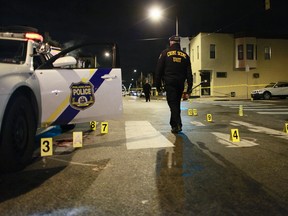 An investigator walks through the scene of a shooting Friday, Jan. 8, 2016, in Philadelphia. A Philadelphia police officer was shot multiple times by a man who ambushed him as he sat in his marked police cruiser, authorities said. (AP Photo/Joseph Kaczmarek)