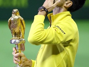 Novak Djokovic of Serbia holds the trophy after winning his Qatar Open men's single tennis final match against Rafael Nadal of Spain in Doha, Qatar on Jan. 9, 2016. (REUTERS/Ibraheem Al Omari)