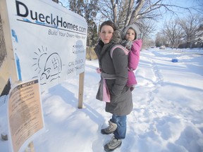 Kathryn Labuik is opposed to a building project in her neighbourhood.  She is standing near a sign that relates to the project with her baby, Addison. (WINNIPEG SUN PHOTO)