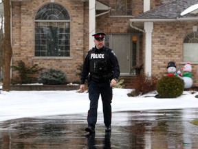 Belleville Police Const. Paul Fyke leaves a home on O'Neill Drive Saturday morning. Police say a man was found inside with gunshot wounds Friday night. Police are still looking for one man.