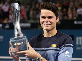 Milos Raonic of Canada smiles with the winner's trophy after winning his men's final match against Roger Federer of Switzerland 6-4, 6-4 during the Brisbane International tennis tournament in Brisbane, Australia, Sunday, Jan. 10, 2016. (AP Photo/Tertius Pickard)