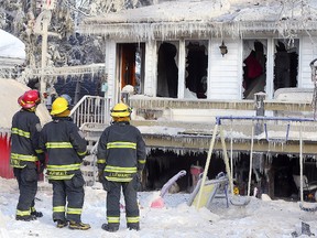 Firefighters examine damage to a house at 108 Cathedral Ave. following a fire that broke out around 2 a.m. Sunday. (Brian Donogh/Winnipeg Sun/Postmedia Network)