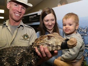Kevin Dungey, education director of Little Ray's Reptile Zoo, holds a caiman at the Diversity of Living Things show in Belleville Sunday.  With him are one-year-old Everett Yokom and his mother, Serena, of Trenton.