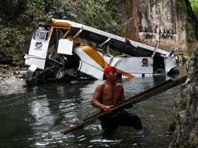 A passenger bus lays in a ravine after falling off the road in Atoyac, Veracruz state, Mexico, Sunday, Jan. 10, 2016. The bus, belonging to the Paso del Toro line, was carrying members of a football team and their relatives along the road connecting the cities of Camaron and Cordoba. According to authorities, at least 20 people were killed and 25 were injured. (AP Photo/Felix Marquez)
